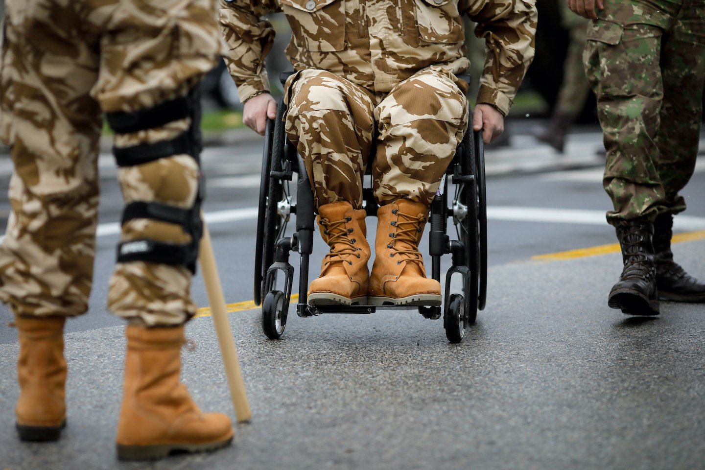 Details with a Romanian army veteran soldier, injured and disabled, sitting in a wheelchair dressed in his military desert camouflage uniform.