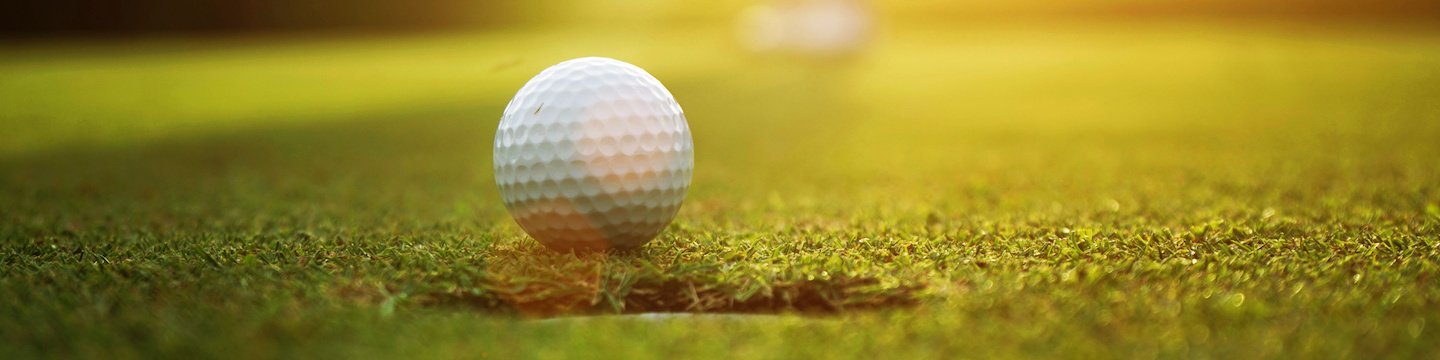 Golf ball sitting near the hole