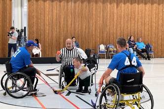 A photo of a faceoff between the staff of the New York Islanders and Viscardi alumni during a game of adaptive hockey.