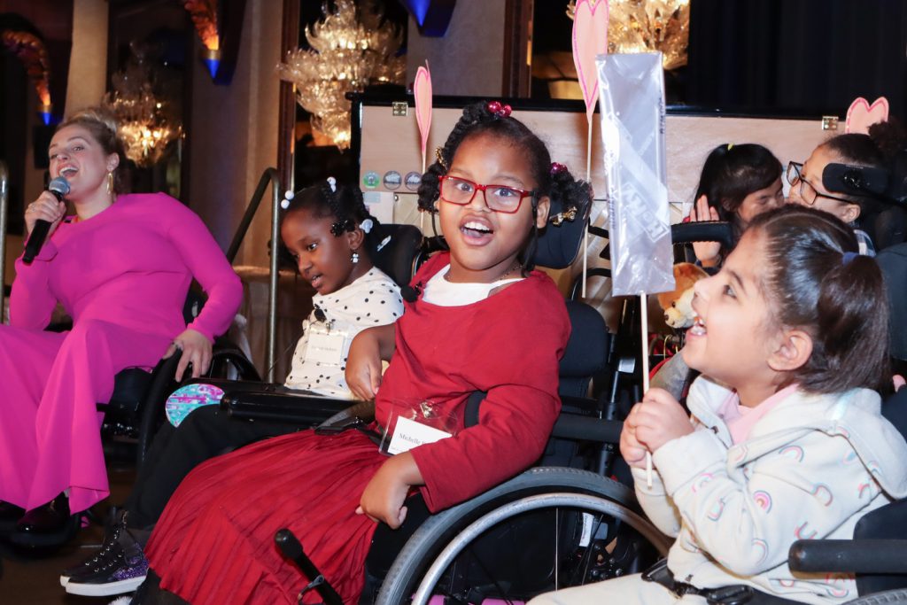 A photo of Tony Award Broadway star Ali Stroker with a group of elementary students with physical disabilities singing.