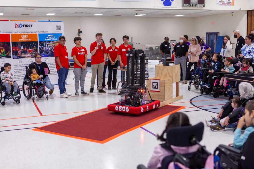 A group of high school students presenting on robots in front of students with disabilities and others.